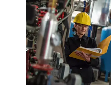 A woman in a factory looking at a binder.