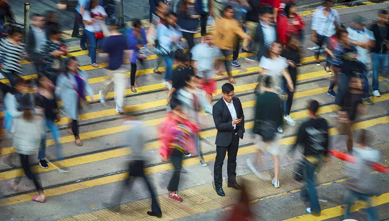 man looking at phone around blurred crowd