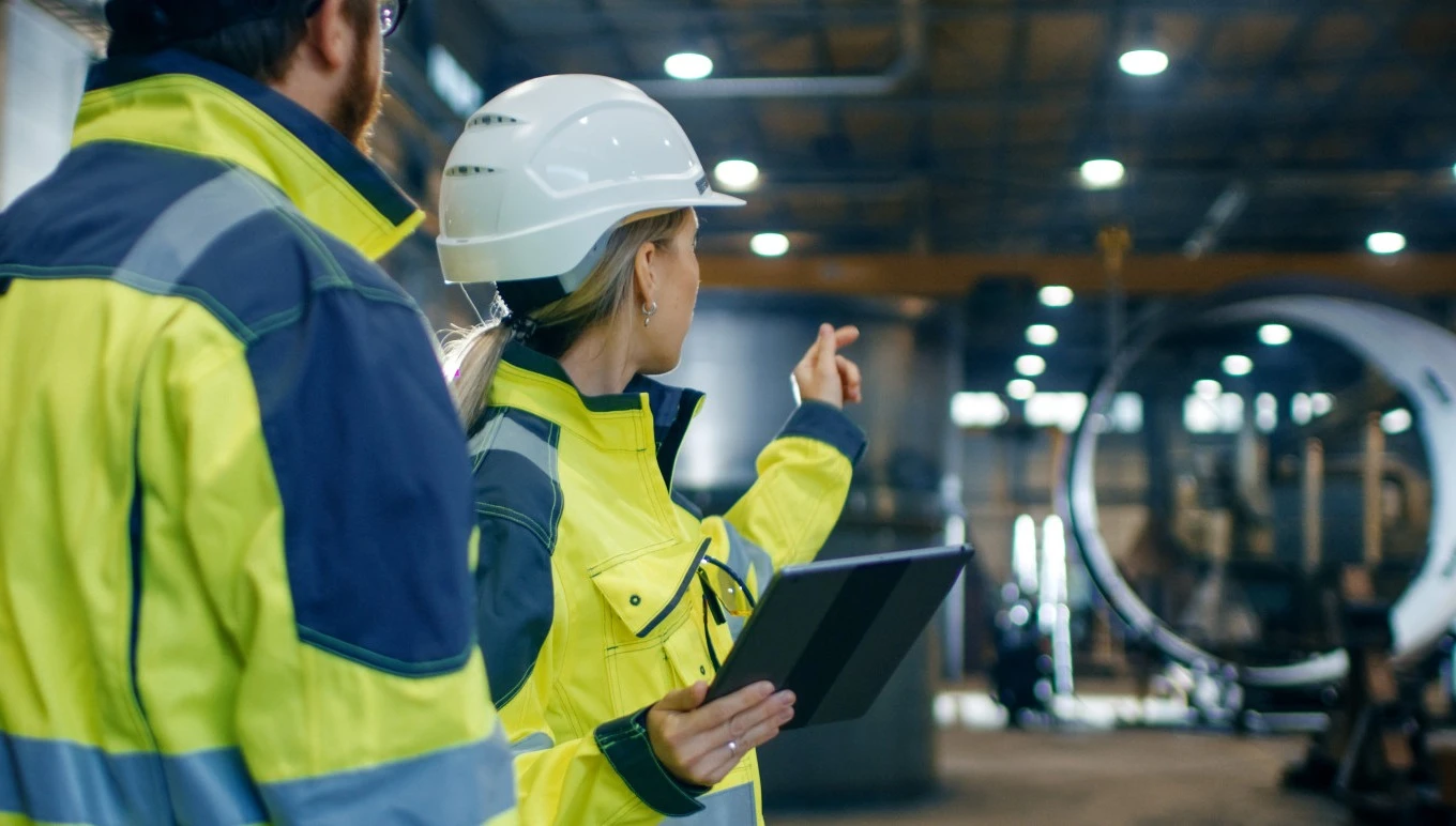 Male and female industrial engineers in hard hats and safety jackets.