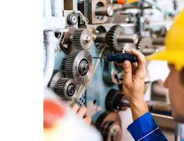 A man using a screwdriver to repair a machine.