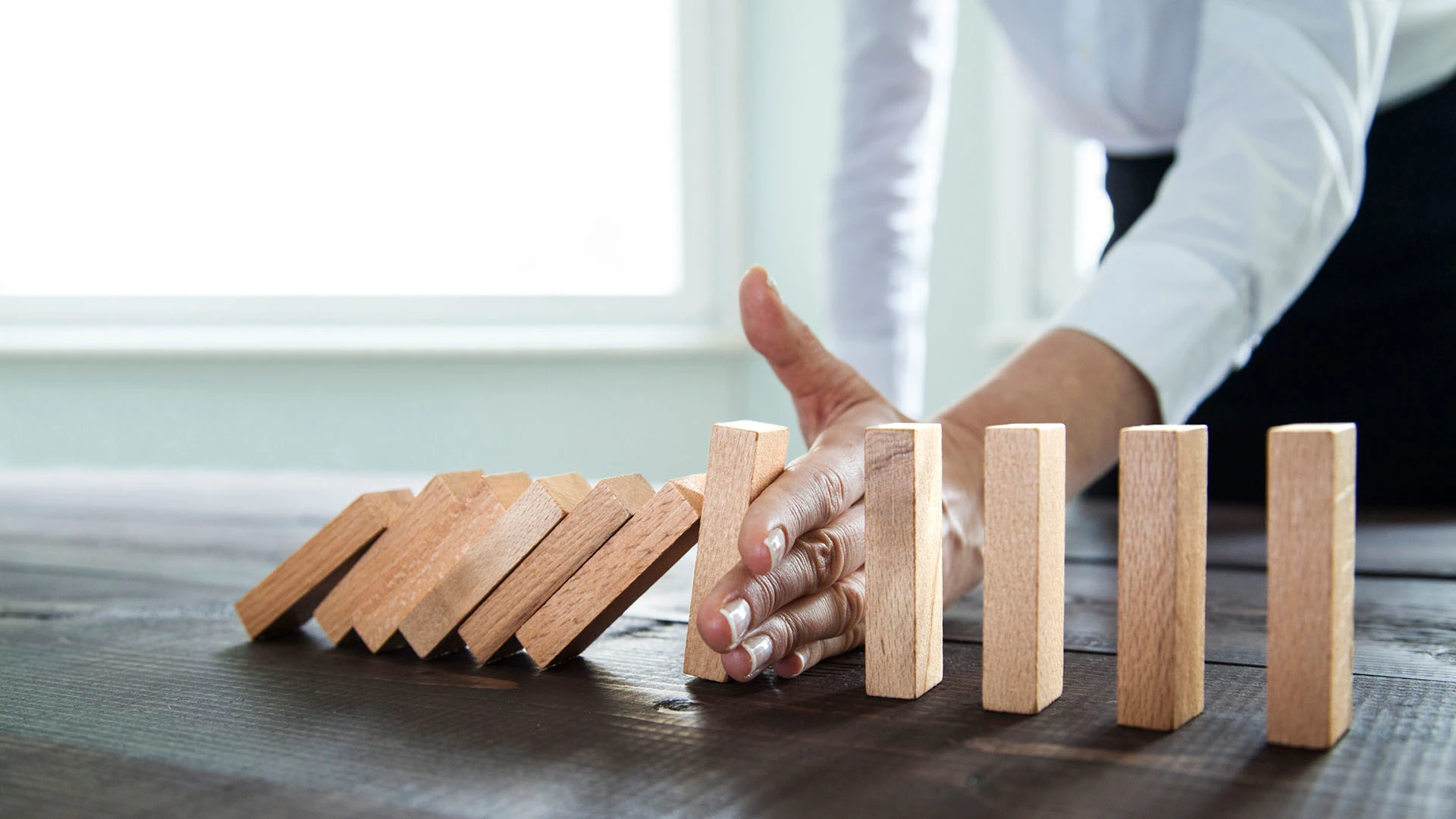 A man stopping small wooden blocks from falling down.