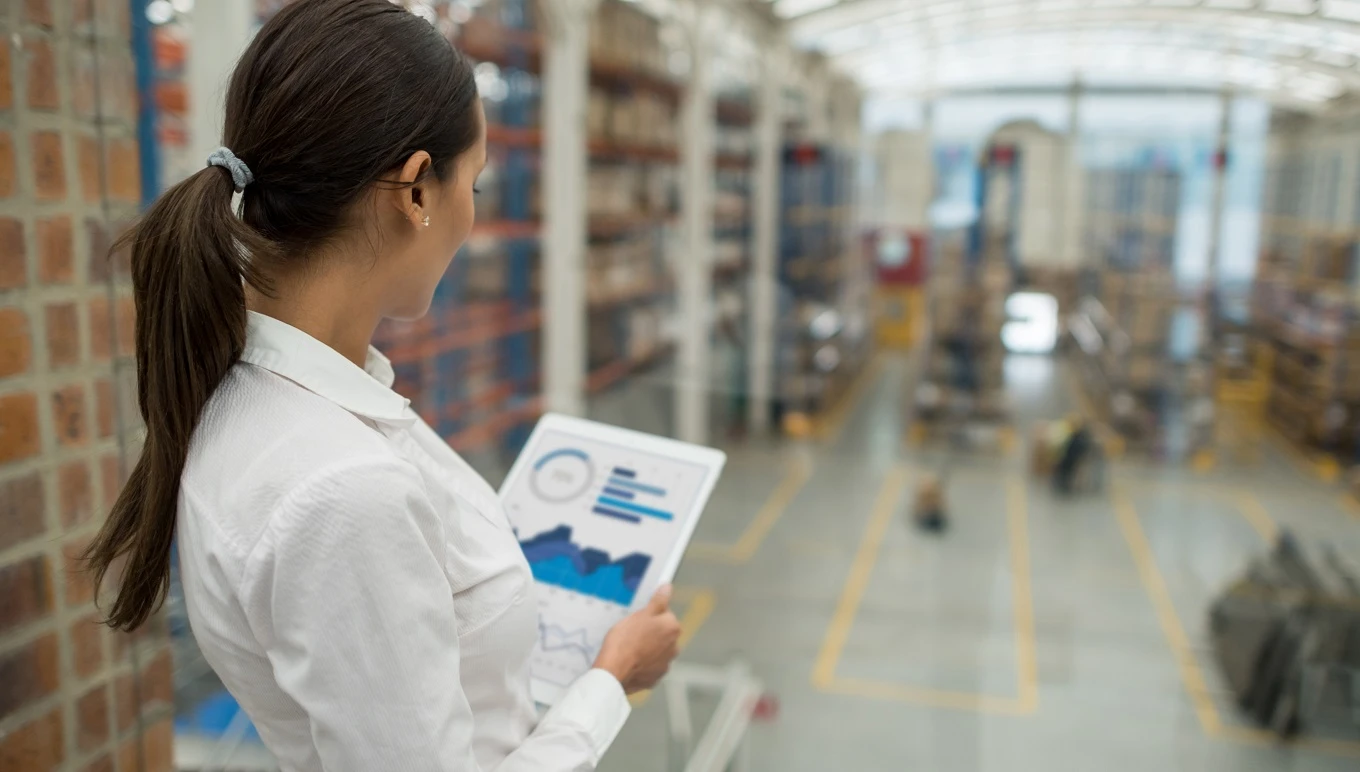 Woman with tablet managing shipments in modern warehouse.