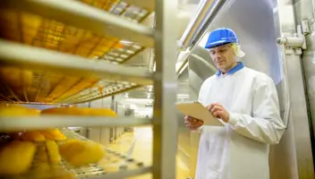 A food facility worker takes stock of products on a cooling rack.