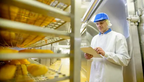 A food facility worker takes stock of products on a cooling rack.