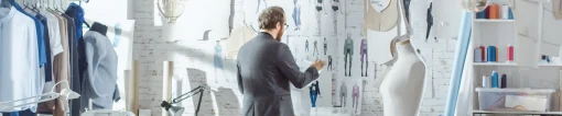 Male designer looks at design drawings for collection.