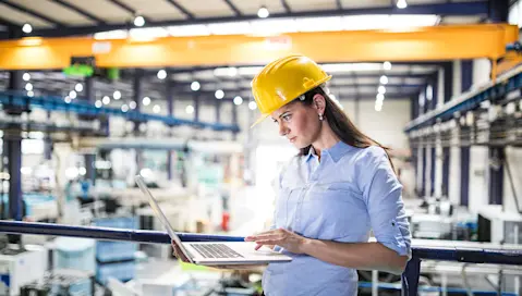 person standing in factory with laptop