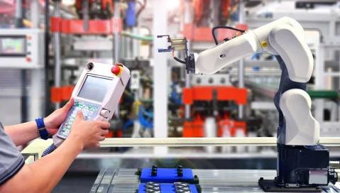 Engineer in factory with an automation robot arm.