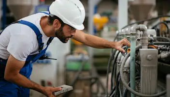 Engineer in hard hat adjusting machine settings in factory