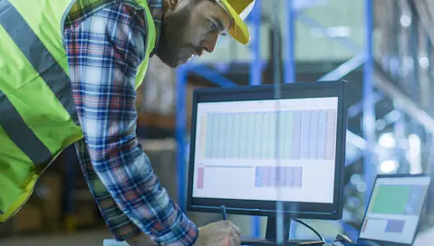 worker on computer with large datasheet