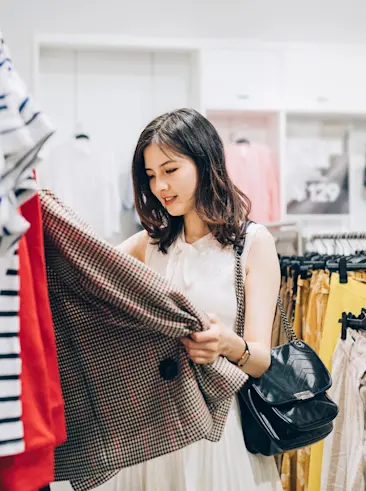 Vrouw die kleding winkelt in een winkel.