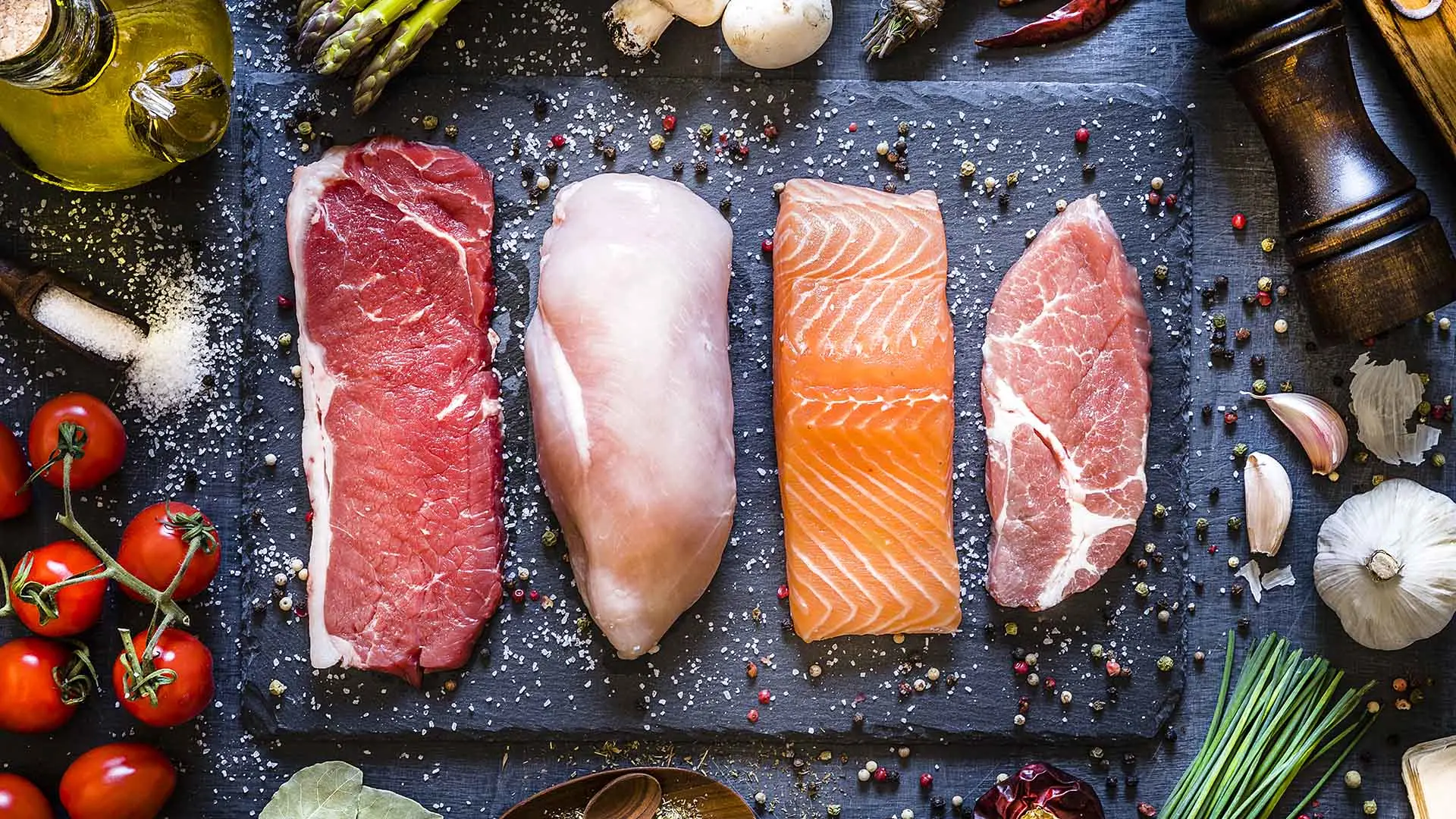 Coupes de viande, de poulet, de saumon et de porc sur une planche à découper de table