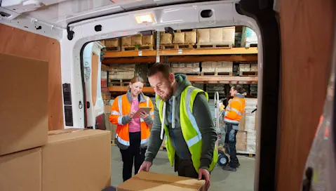 Warehouse team loading delivery van with boxes