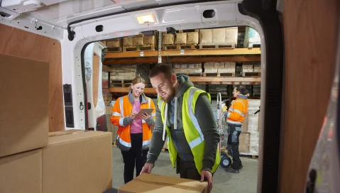 Warehouse team loading delivery van with boxes