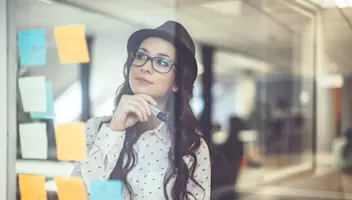 Businesswoman reviews sticky notes on glass wall