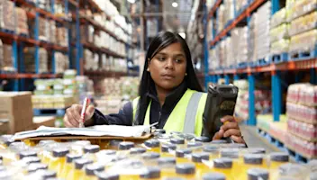 A food distribution professional reviews a pallet of beverages and accompanying documentation.