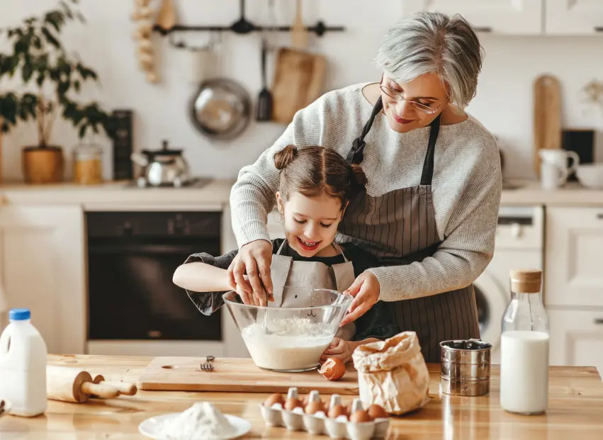 Grandmother teaching granddaughter how to bake cookies in a home kitchen