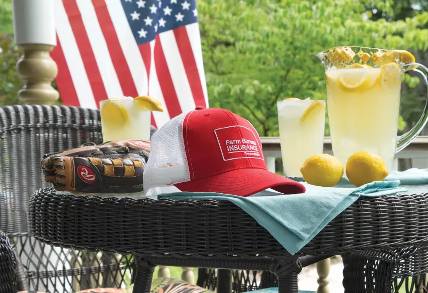 Farm Bureau Insurance of Tennessee red hat sitting on patio table with lemonade and baseball glove