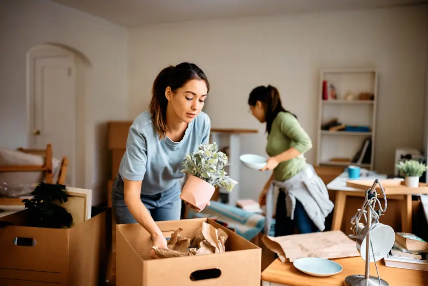 Two women roommates unpacking boxes of furniture in their new apartment that they are renting