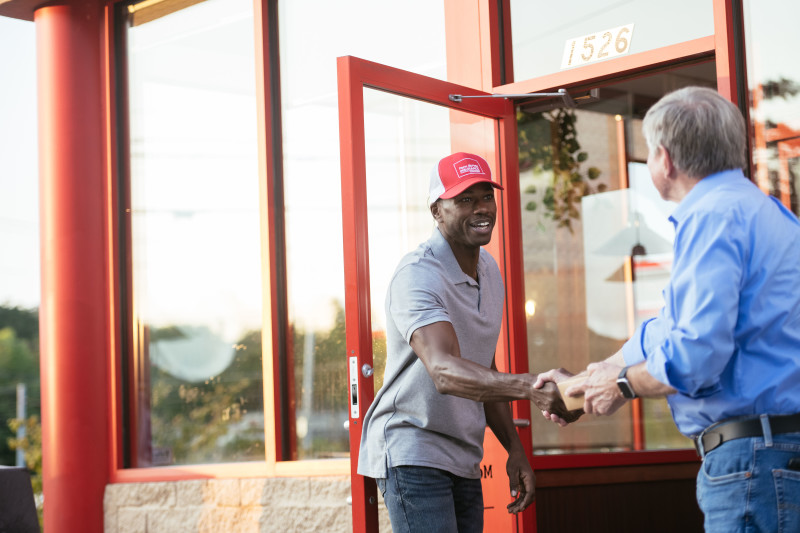 Two men shaking hands outside of a business