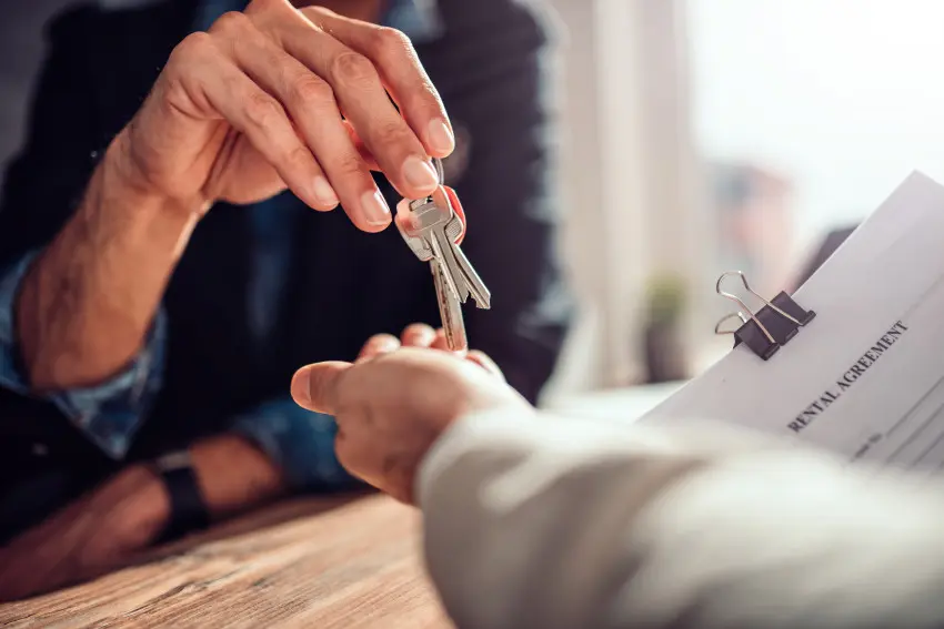 Landlord handing keys to a new tenant signing a rental agreement