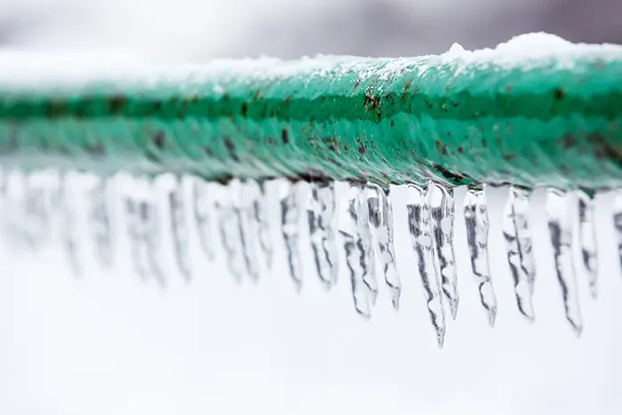 Frozen pipe with a line of icicles under the bottom of the frozen pipe