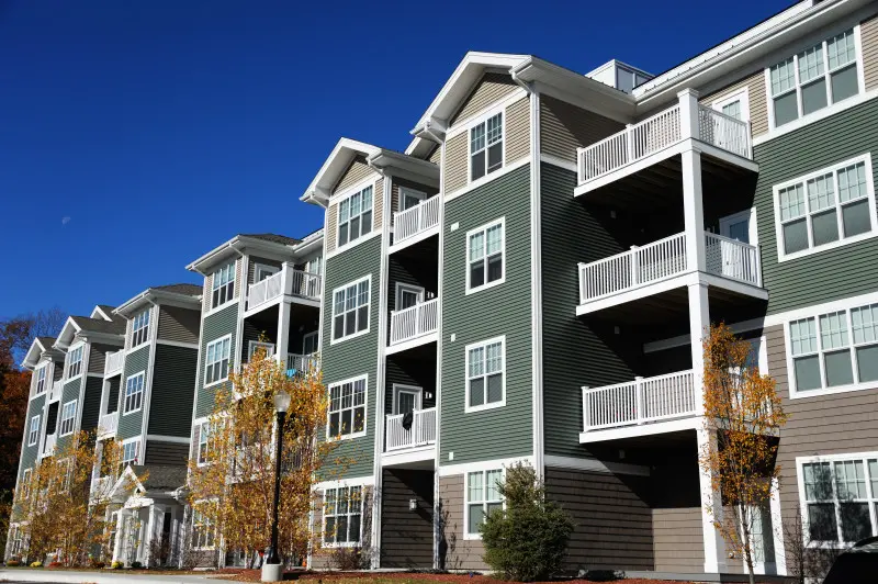 Large green and white apartment complex with multiple levels and apartments available for rent