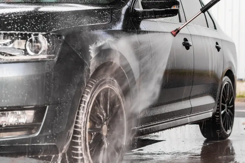 Car wash in progress, using a high-pressure washer to clean the exterior