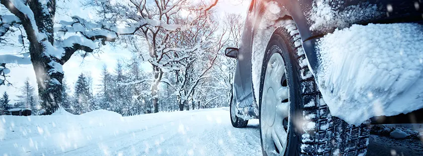 Black car driving through heavy snow during a winter snow storm