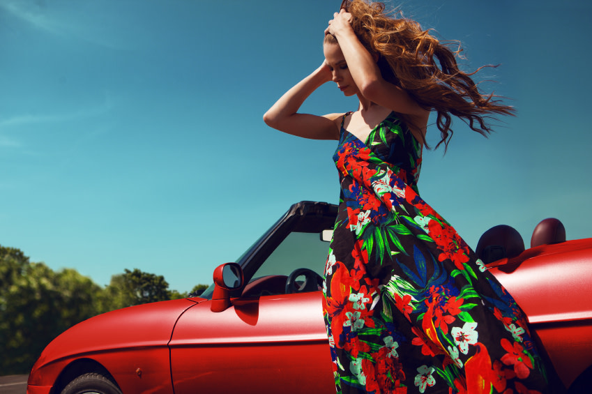 Frau im langen Kleid vor einem Auto