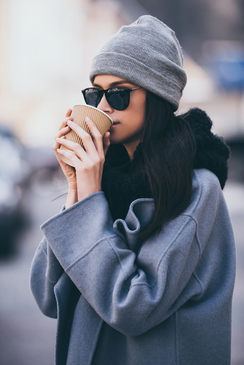 Junge Frau mit Kaffeebecher und Wintermantel