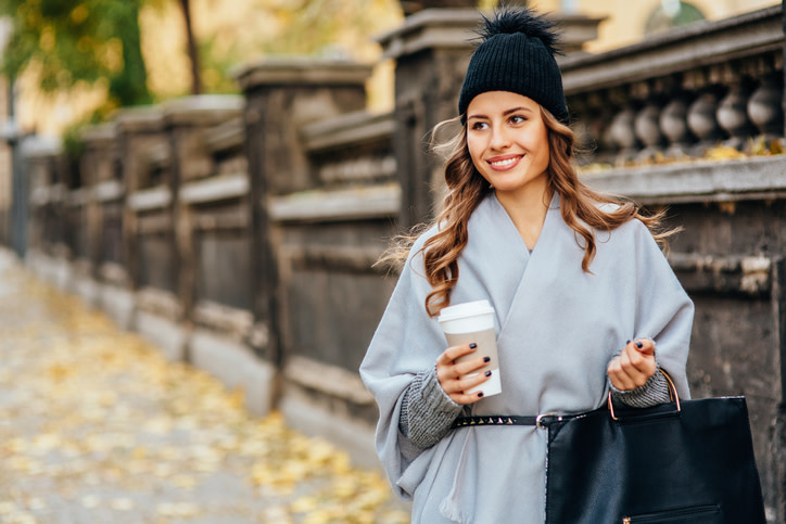 Junge Frau im Winterkleid mit Kaffee und Handtasche