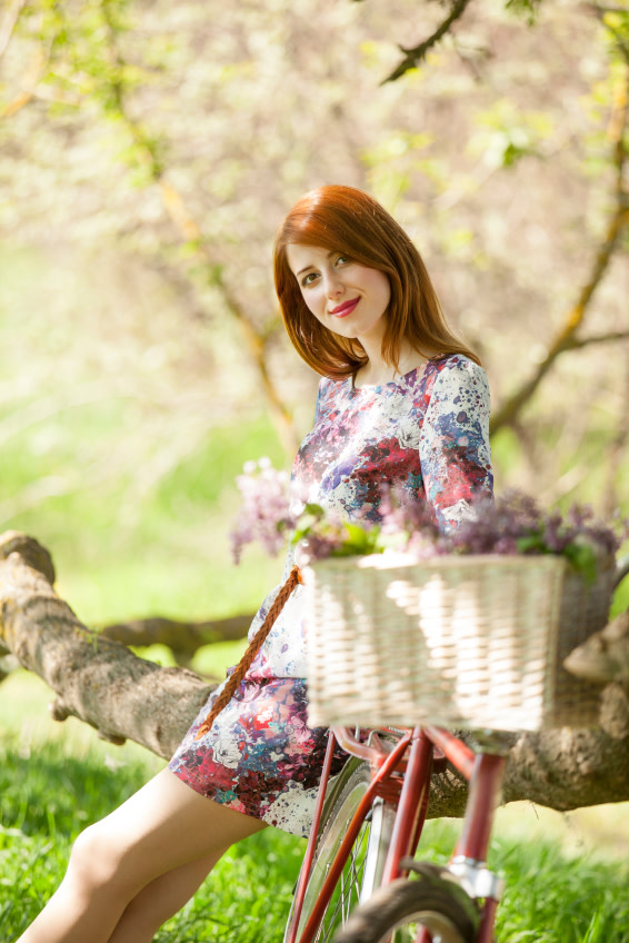 Junge Frau auf dem Fahrrad im Blumenkleid