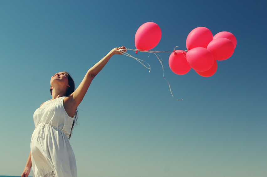 Young pregnant woman holding red balloons. Photo in old color im
