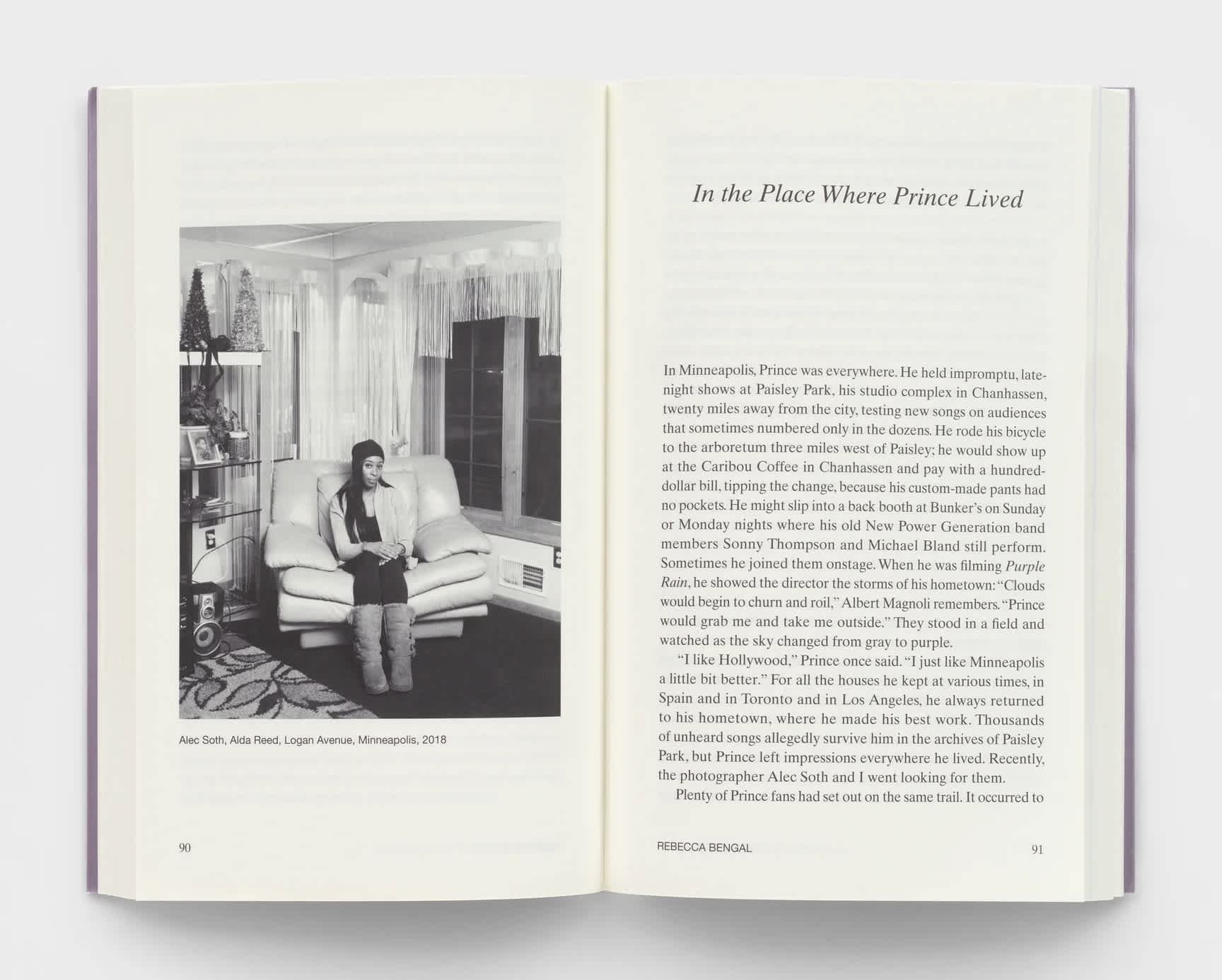 Open book with a black and white photograph on the left page and essay text on the right page.