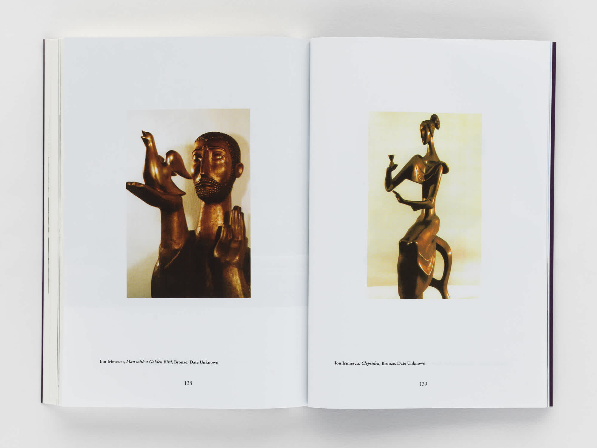 Open book with a photograph of a sculpture on each page.