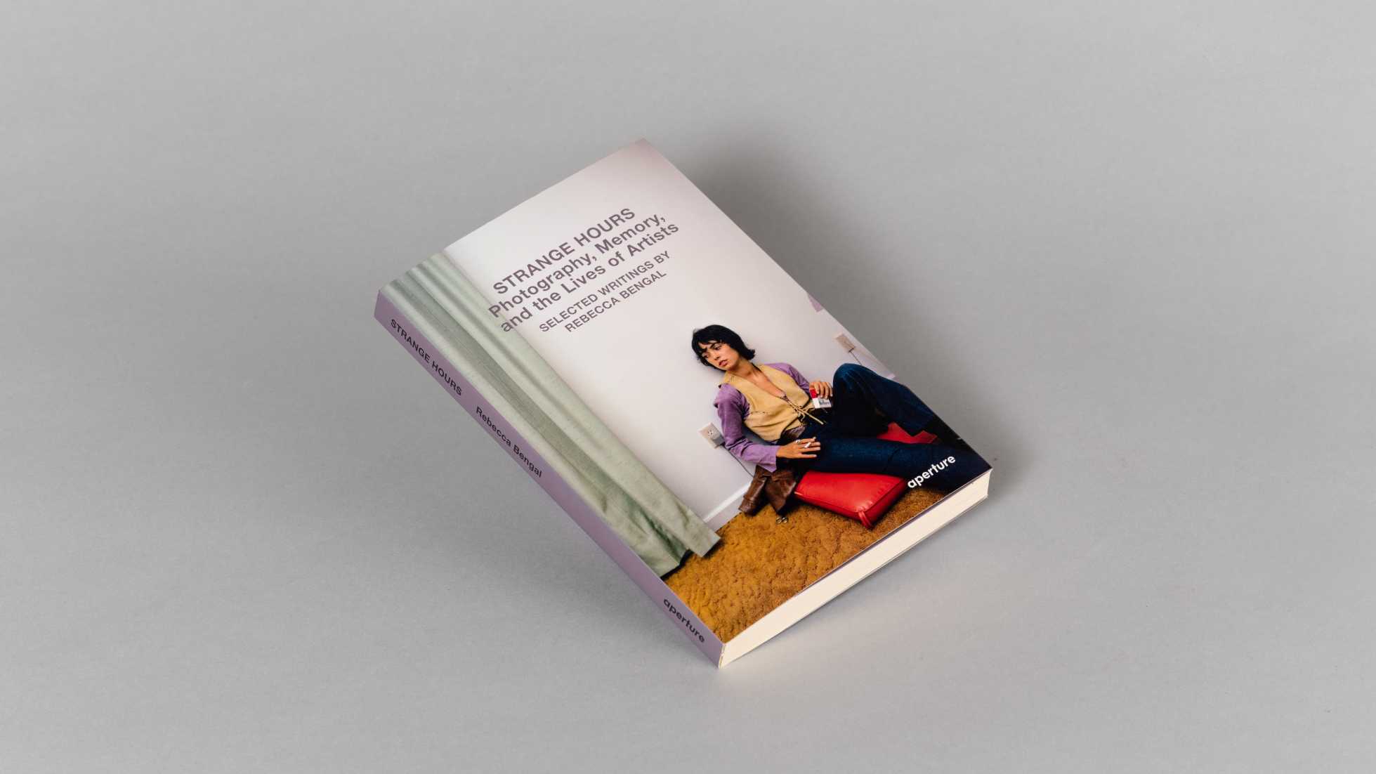 Book cover with purple text over a color photograph of a woman seated on the floor smoking a cigarette.