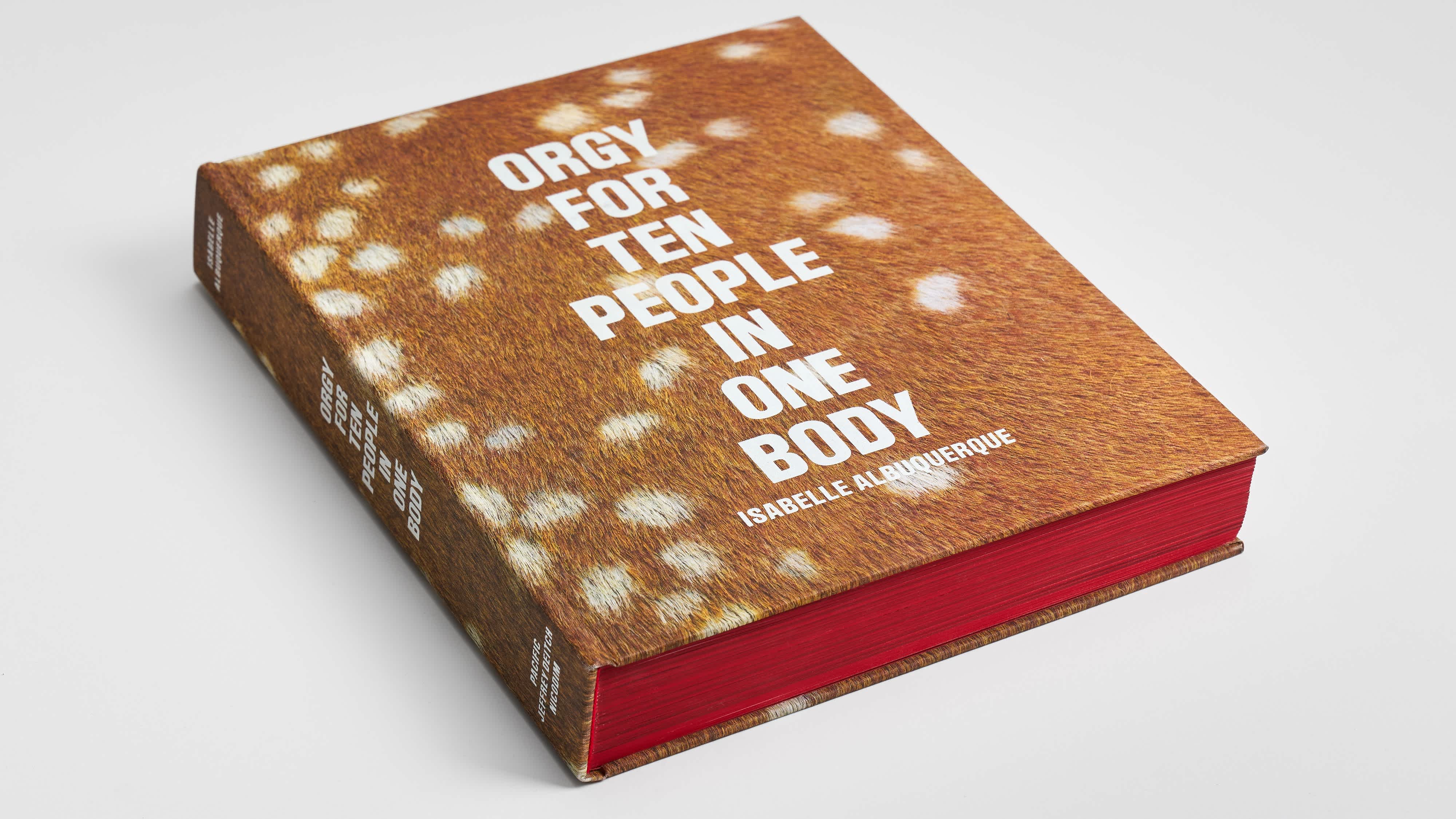 A book lies on its back with the front cover, spine and bottom edge visible. The cover of the book is a speckled-fawn print and the title is printed in white-block letters in a single, center-justified column.