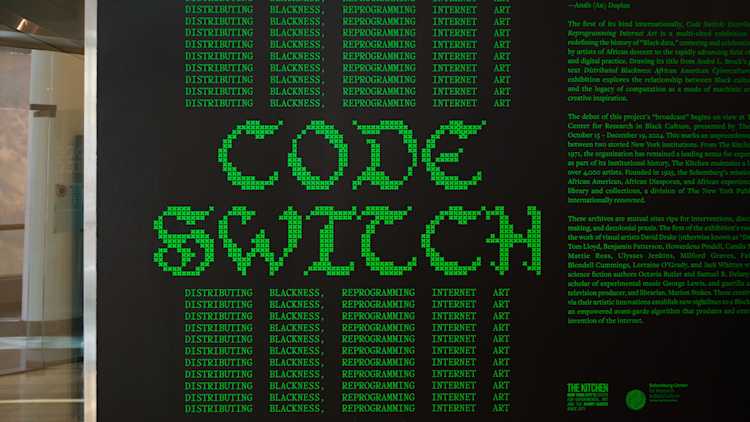 Black wall with green pixelated text reading “CODE SWITCH.” Surrounding words repeat: “DISTRIBUTING BLACKNESS, REPROGRAMMING INTERNET ART.” Exhibition and program details are partially visible to the right.