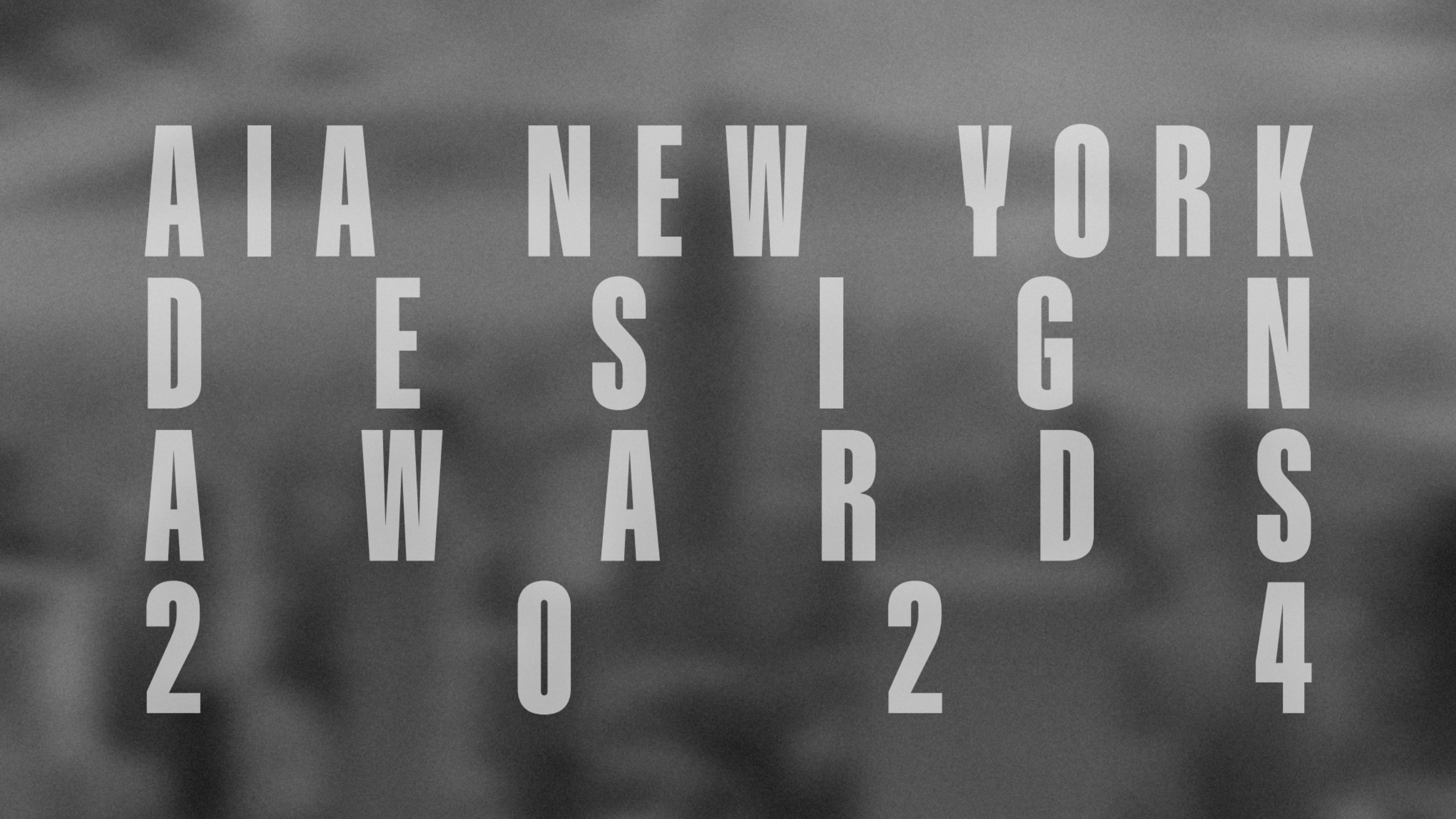 Grey text over a blurry black and white photo of New York City.