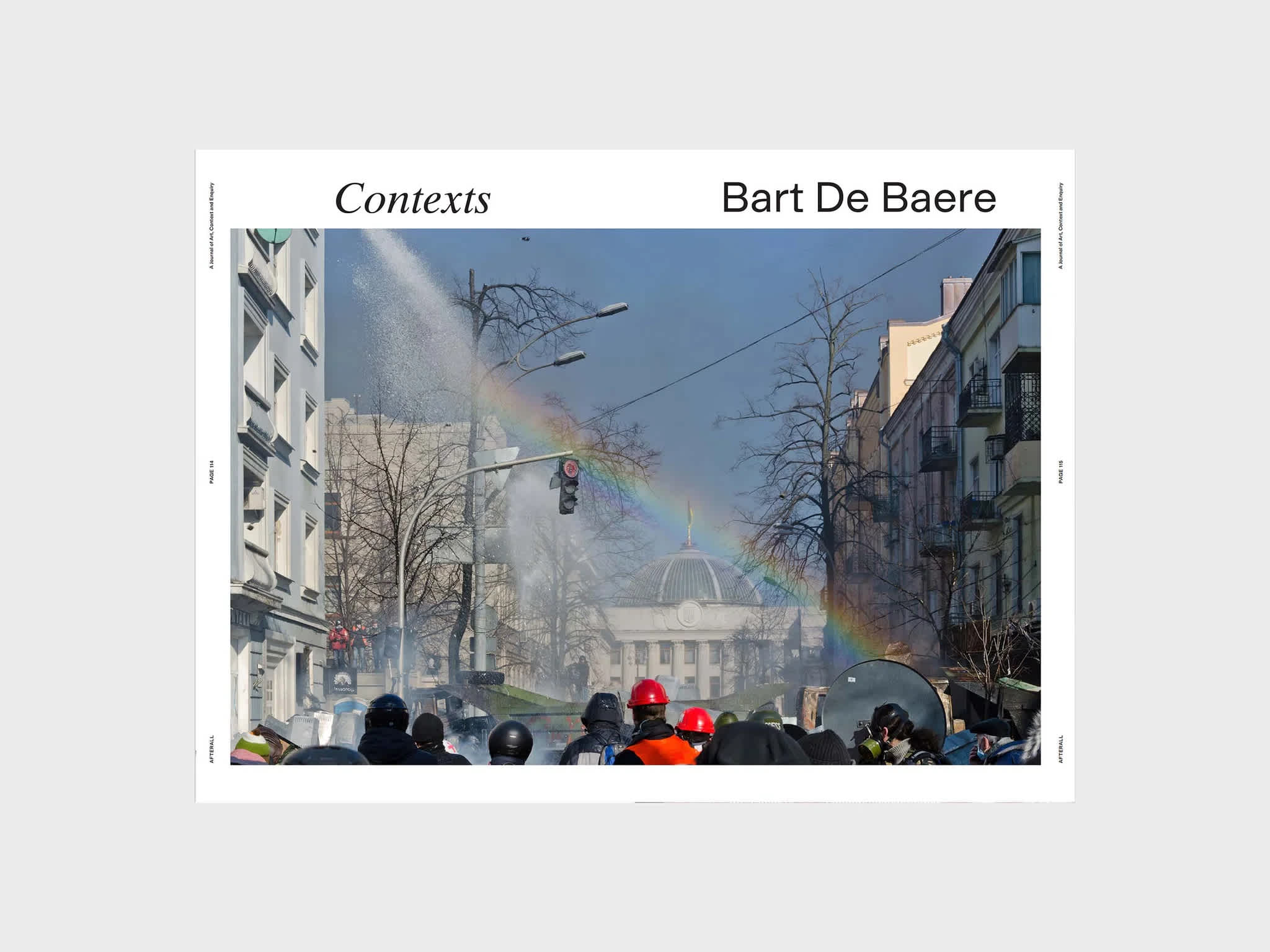 Centerfold magazine spread. The section title and author are on the top of each page. The image spread across both pages, features a rainbow stretching between two sides of a street. Below the rainbow is a crowd of people.