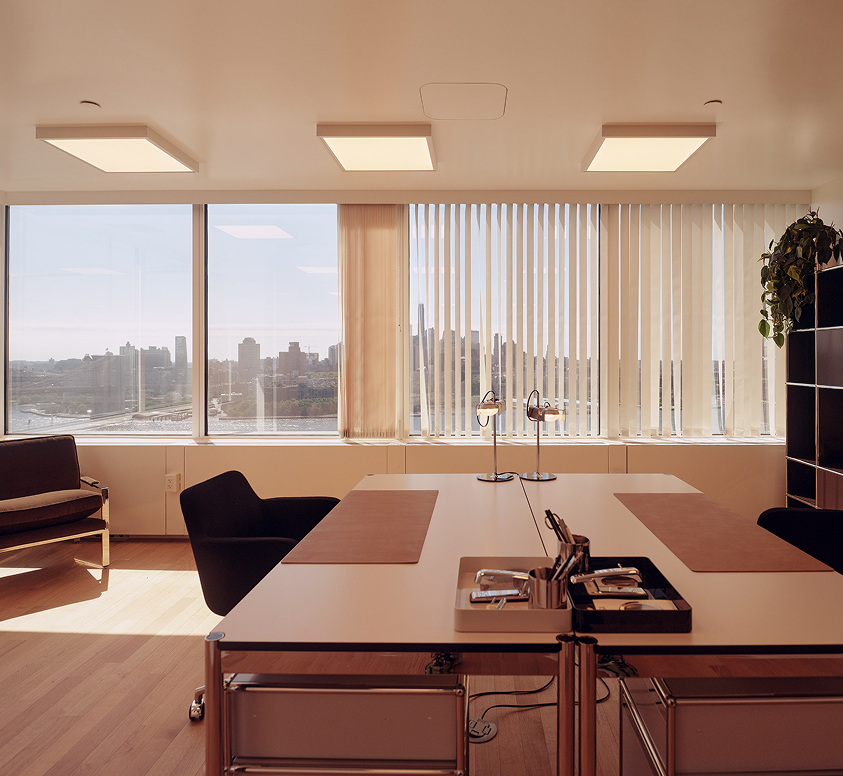Elegant and modern office space with big windows overlooking the river with a view of the Brooklyn Bridge.