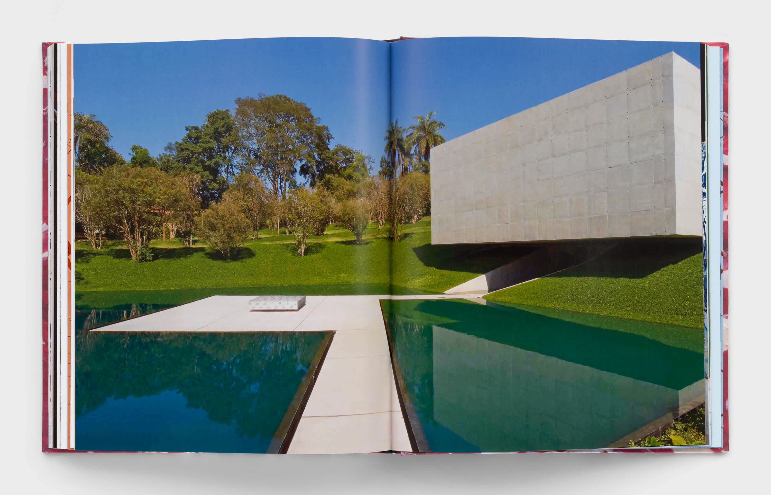 Open book with centerfold of landscape showing trees, a concrete building and swimming pool.