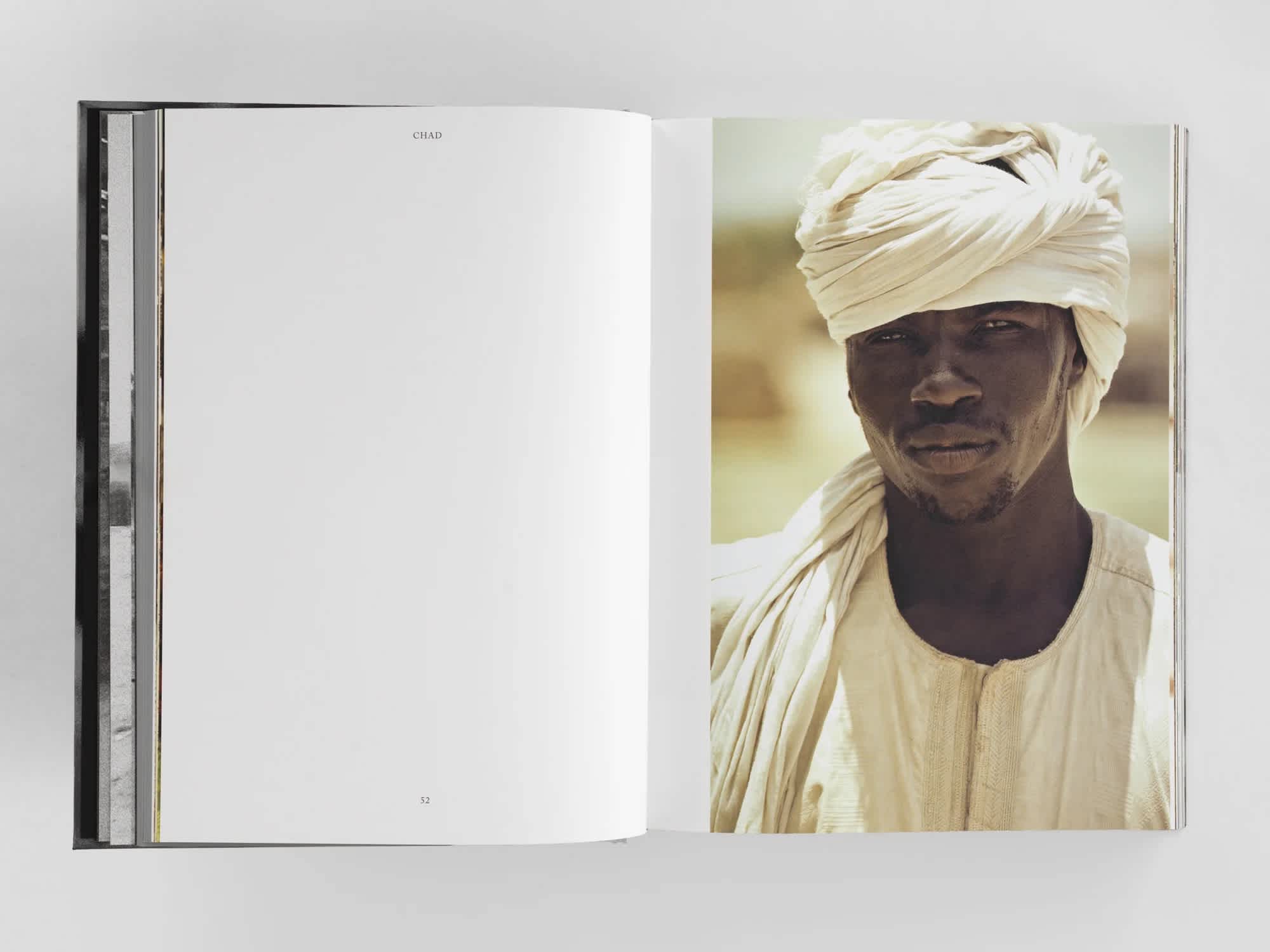 Open book with plain white left page and photograph of a man dressed in white robes on the right.