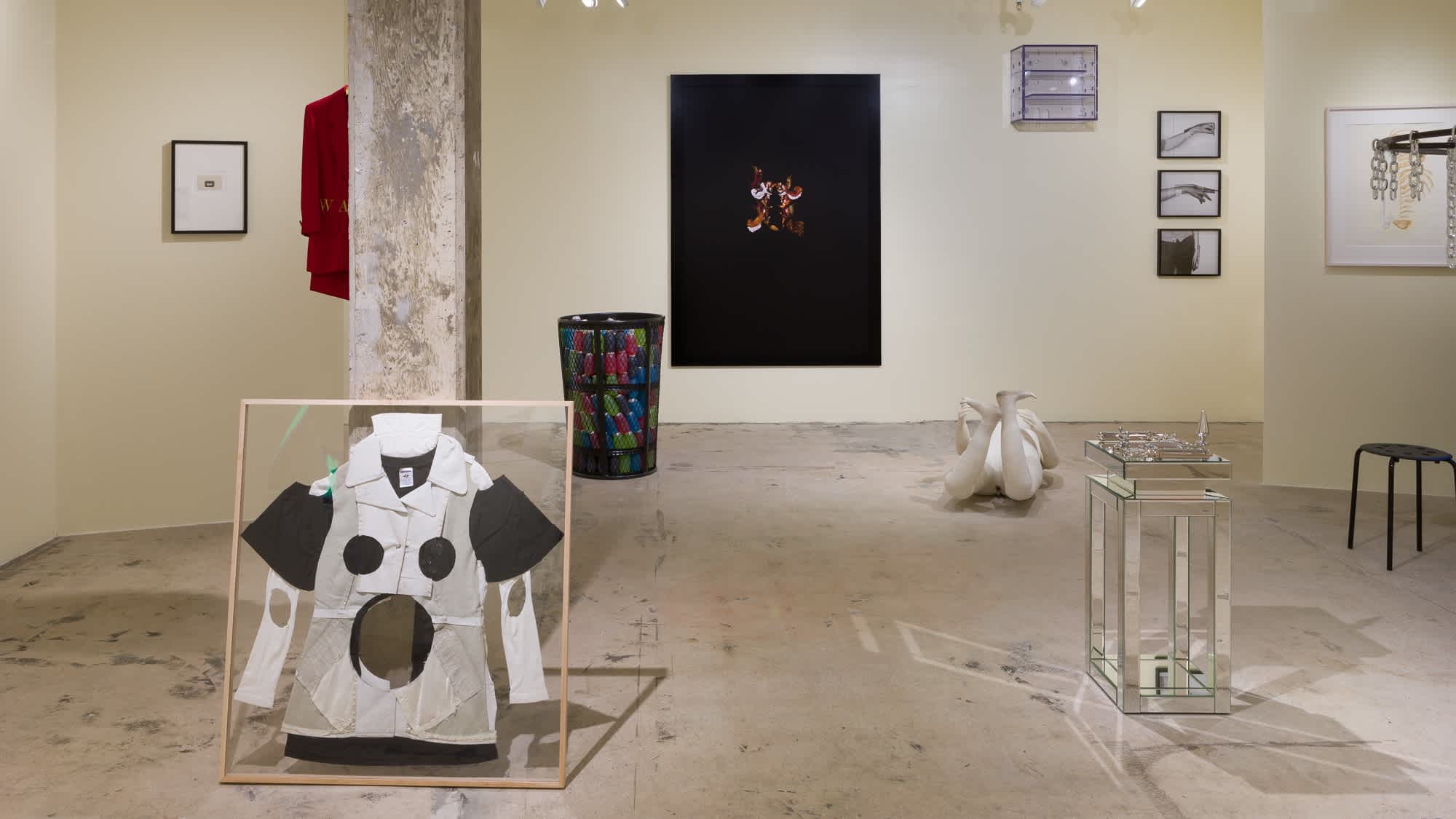 Exhibition photograph that features several sculptures on the floor and framed works on the wall.