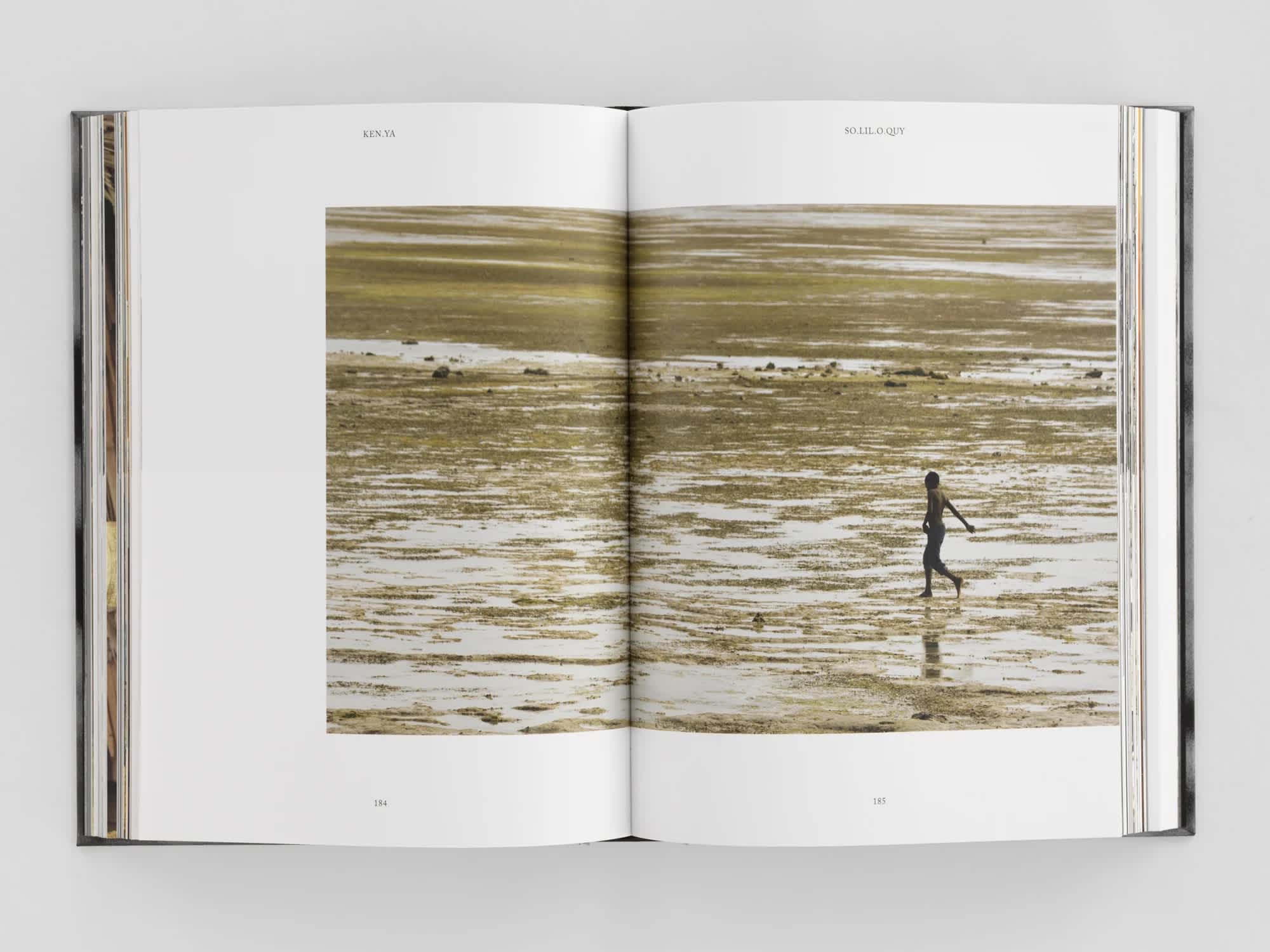 Open book with photo of a person walking in a river stretching across both pages.