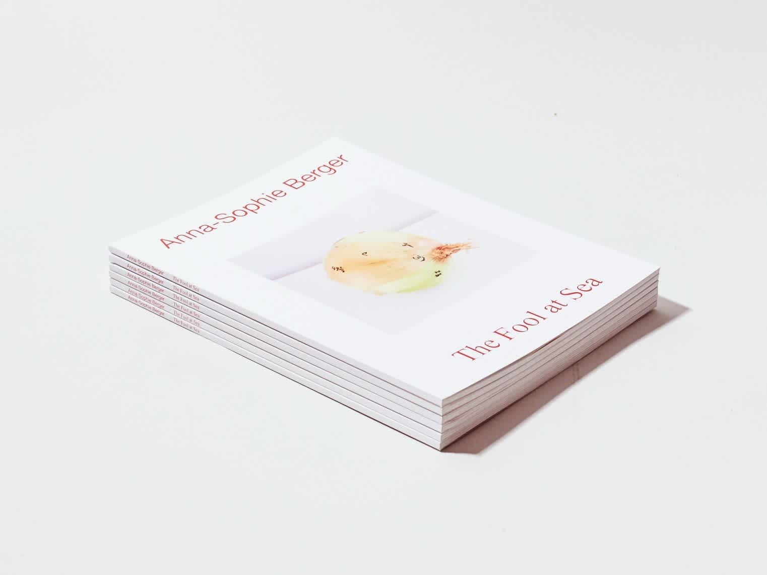A stack of six white books with red text. A photograph of an onion separates the title and the author's name.