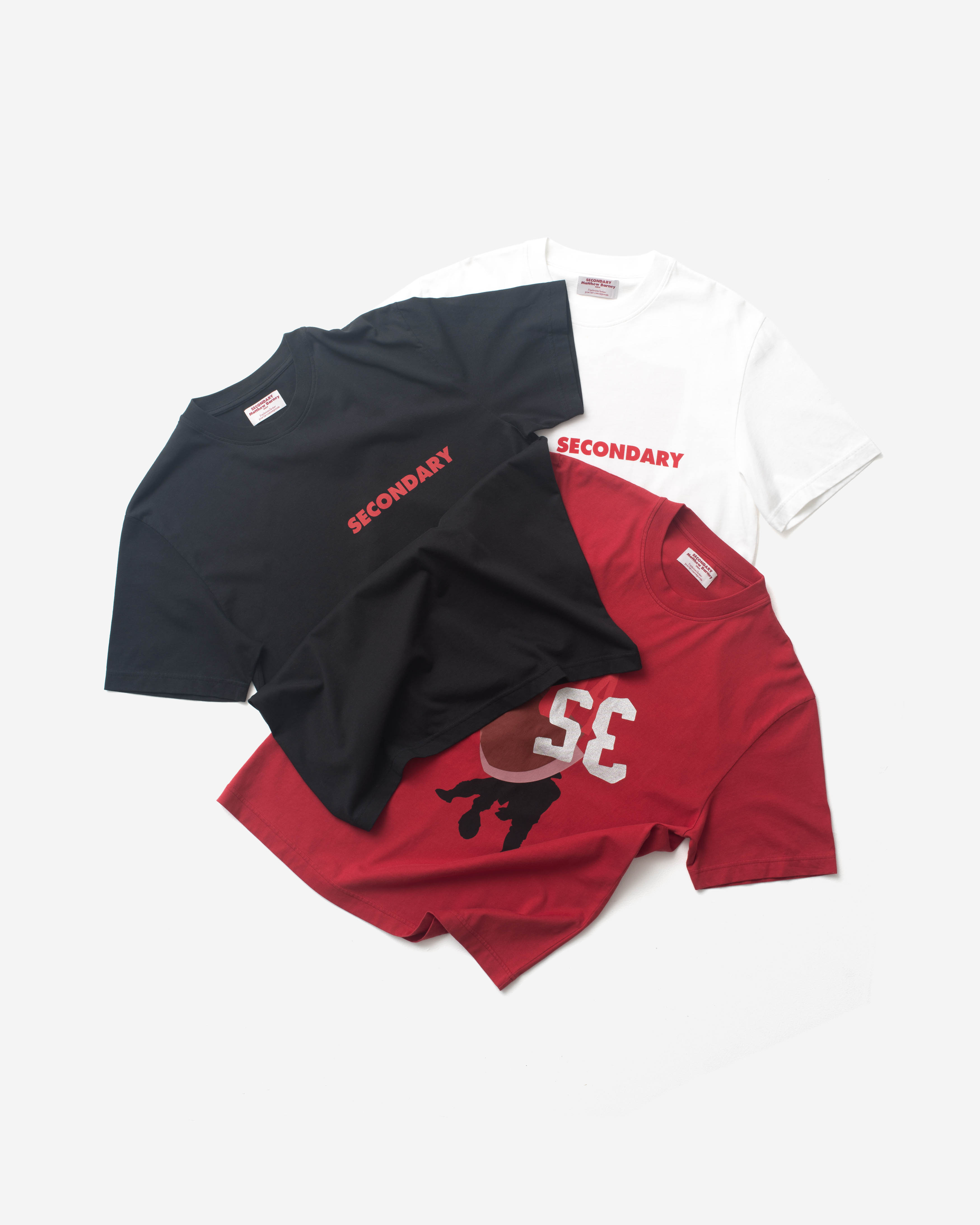 Image of three t-shirts laying on a grey floor.