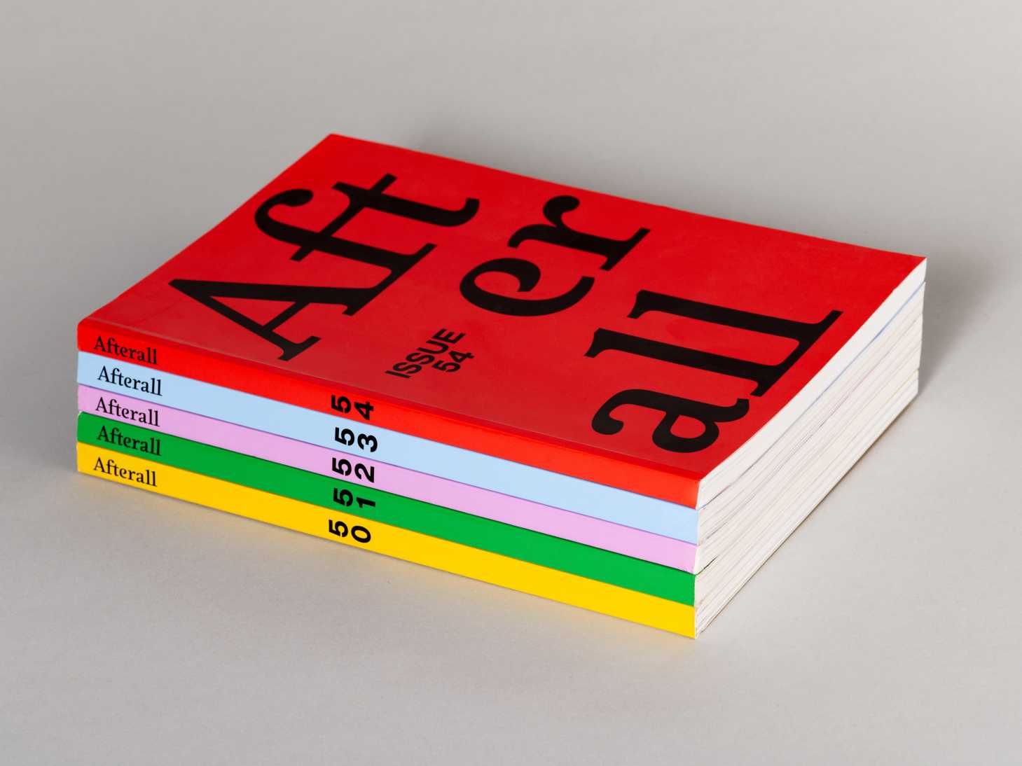 Stack of alternating magazine covers, all with the title "Afterall" and spines displaying their issue number. The covers are red, yellow, green, purple and blue.