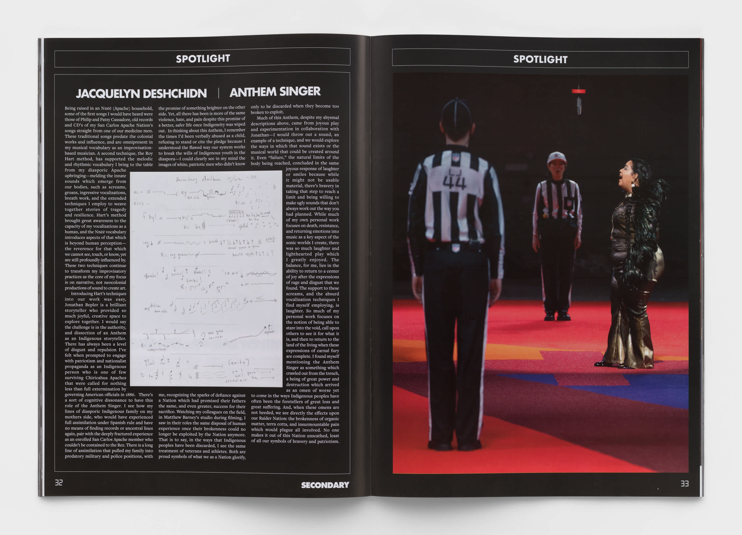 Book interior which features a full page of text on the left and an image from the installation, 'Secondary' by Matthew Barney on the right. The text is white on black background. The image features two referees on a red, orange and blue carpet. A woman in a black dress is in side-profile, singing.