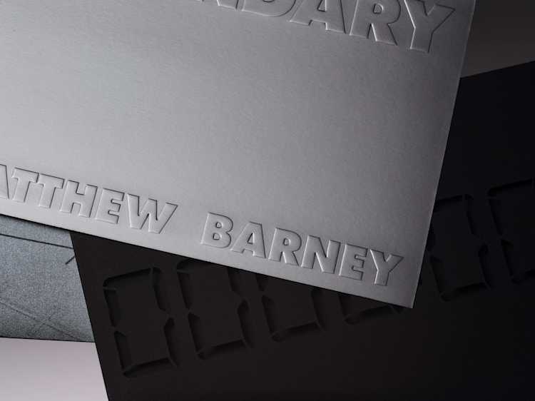 Close up shot of a silver museum exhibition invite which says "Secondary, Matthew Barney".
